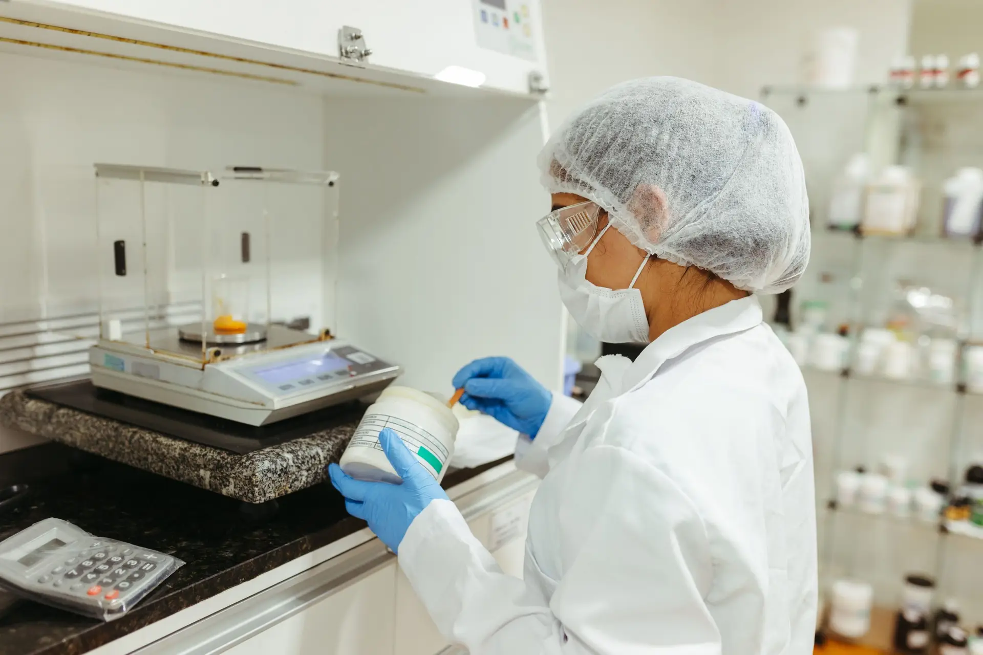 A scientist in a lab coat conducts an experiment in a laboratory, showcasing precision and safety protocols.