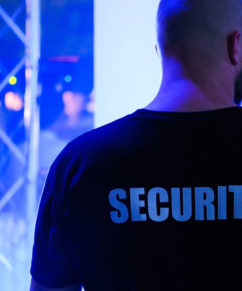 A security guard wearing a black shirt in a dimly lit nightclub.