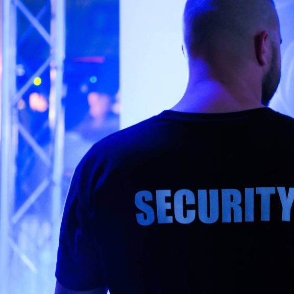A security guard wearing a black shirt in a dimly lit nightclub.