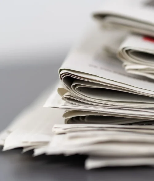Close-up of stacked newspapers on a table, representing media and journalism.